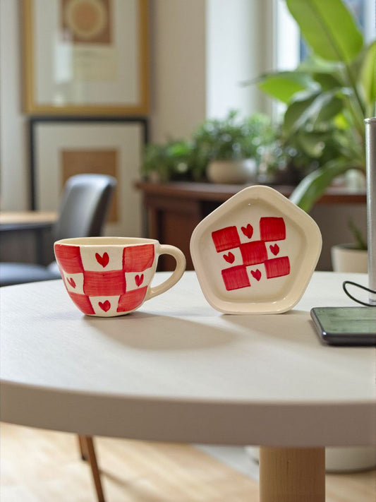 Ceramic cup and plate with red heart pattern on a table in a home setting